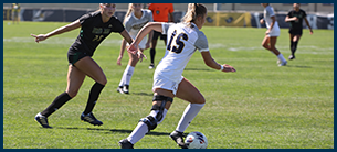 women's soccer athlete kicking the ball down the field.